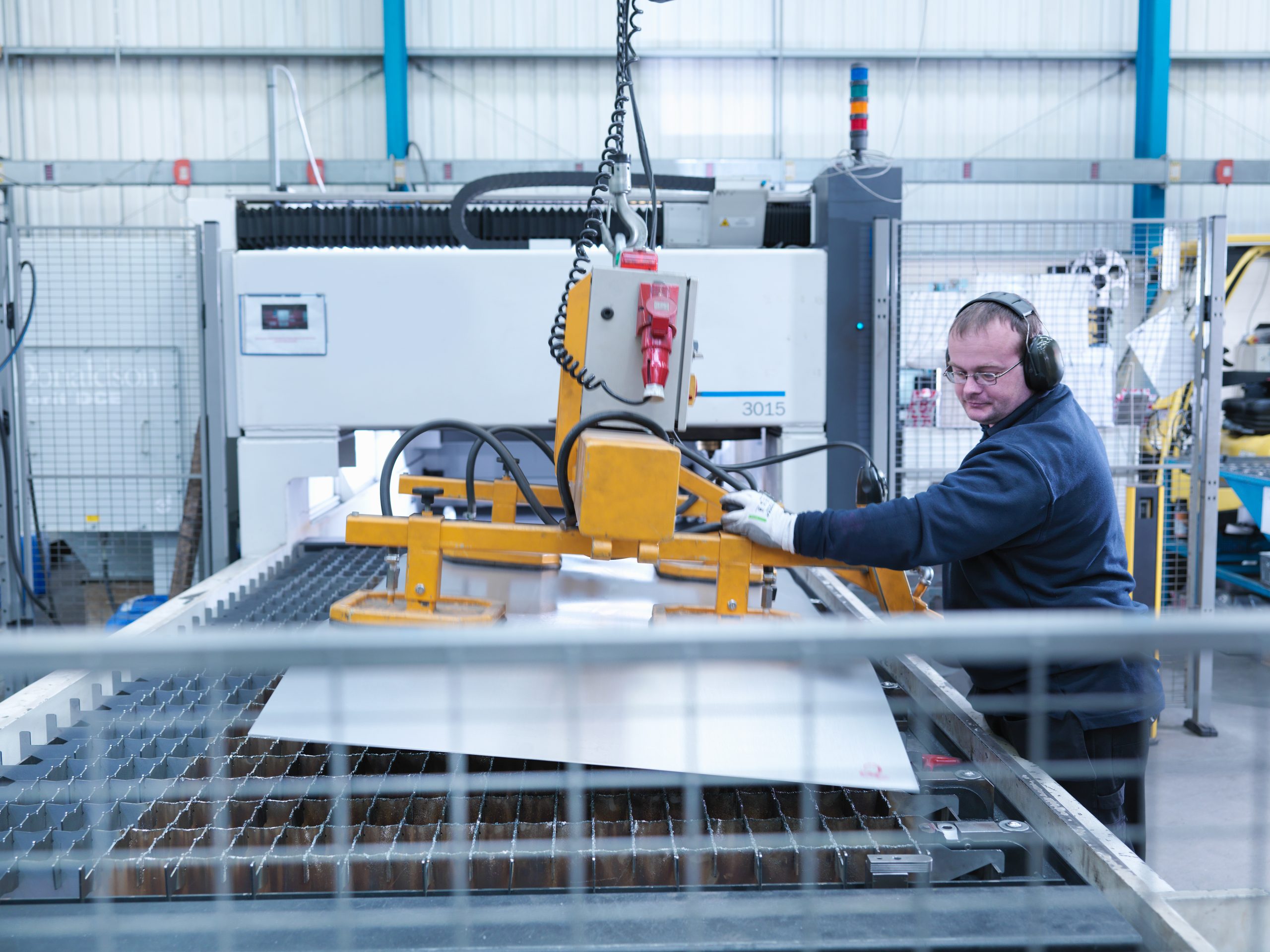 Engineer loading sheet metal into laser cutter in engineering factory