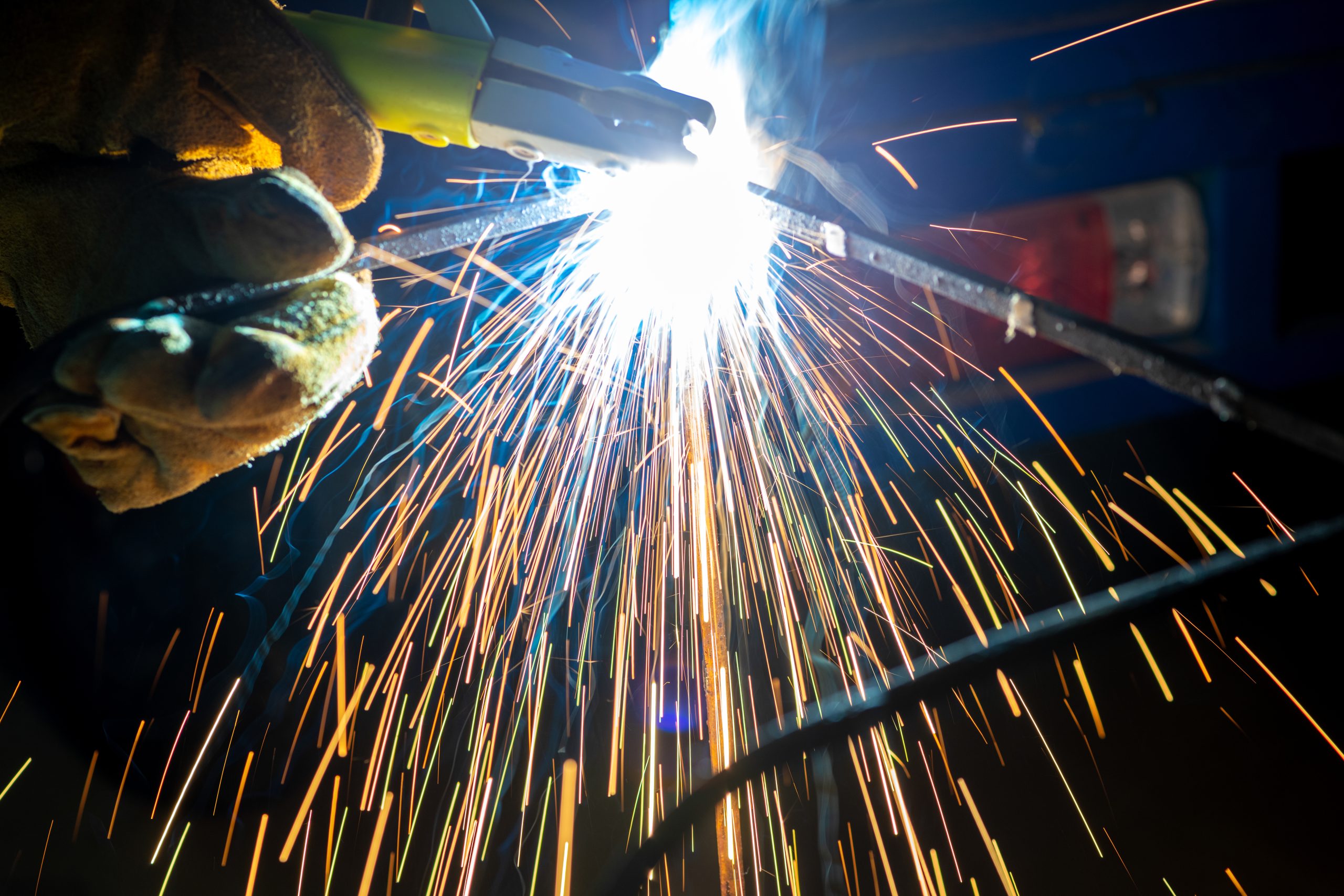 Young man with protective mask welding in a factory